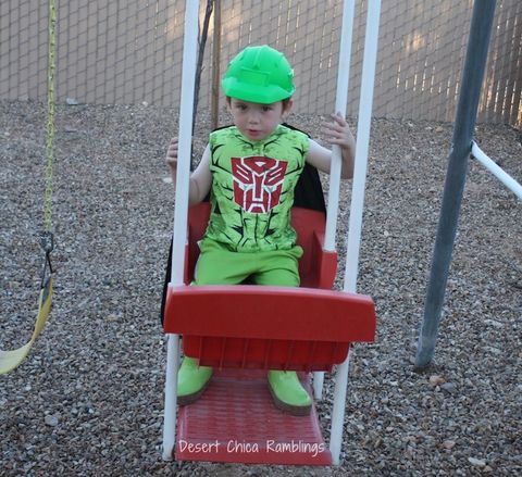 transformers halloween costume ideas, boy on a swing wearing a green outfit with green helmet