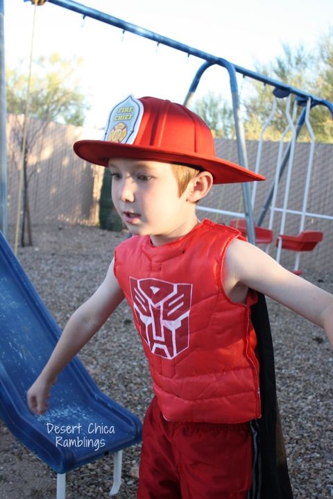transformers halloween costume ideas, small boy in a playground wearing a red costume with a transformers logo
