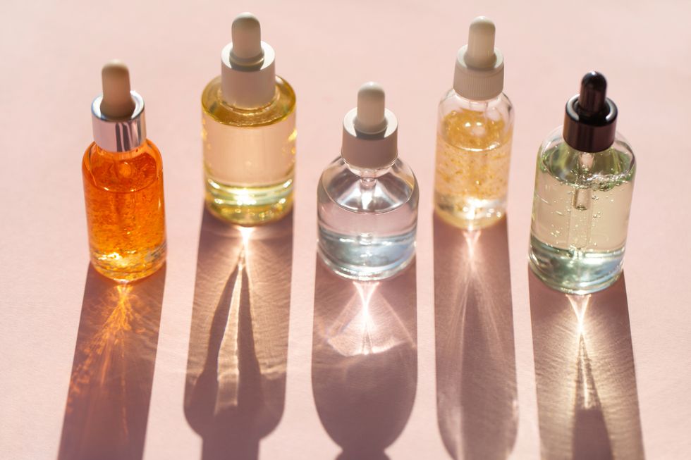 transparent bottles of aromatic cosmetic products placed in row on pink background trendy selfcare products of the year
