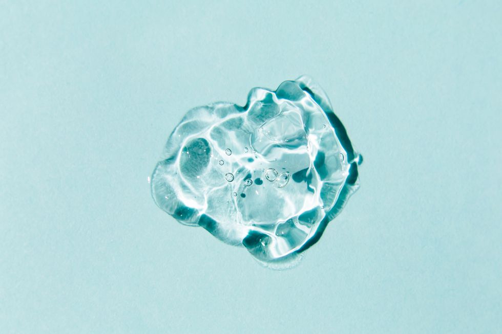 transparent drop of gel on blue backgroundliquid hyaluronic acid gelflat lay top view, copy space