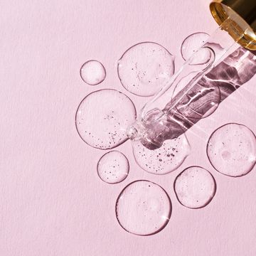 transparent drops of hyaluronic acid and glass pipette on pink background