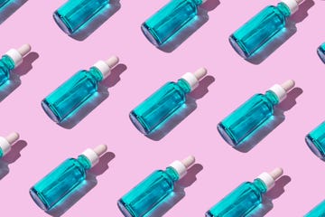 transparent liquid dropper 
and blue bottle on pink pastel background