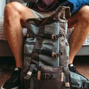 man packing travel backpack in bedroom