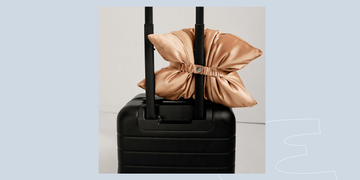 black suitcase with a decorative satin pillow attached to the handle