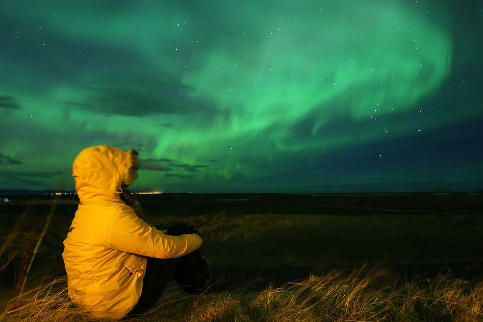 Traveller Looking Admiring Northern Lights During Aurora Storm in Iceland