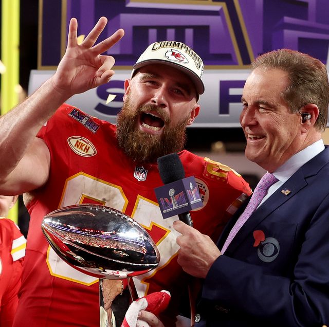 travis kelce smiling and gesturing to fans while doing an interview with cbs commentator jim nantz after the super bowl