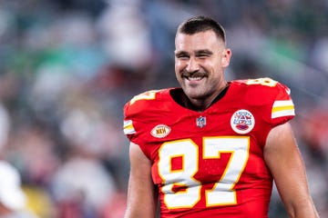 travis kelce smiling while wearing his chiefs no 87 football jersey