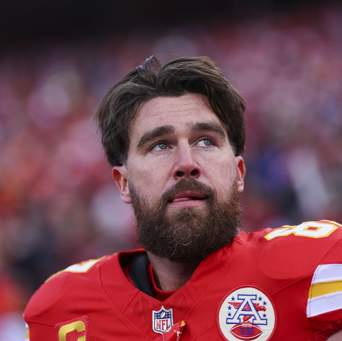 travis kelce looking up with his hand against his football uniform