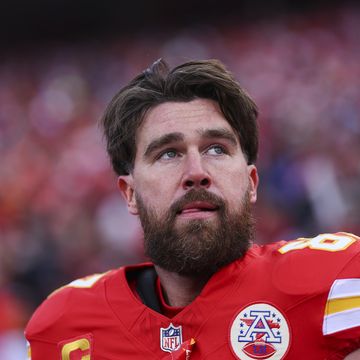 travis kelce looking up with his hand against his football uniform