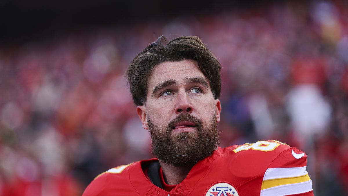 travis kelce looking up with his hand against his football uniform