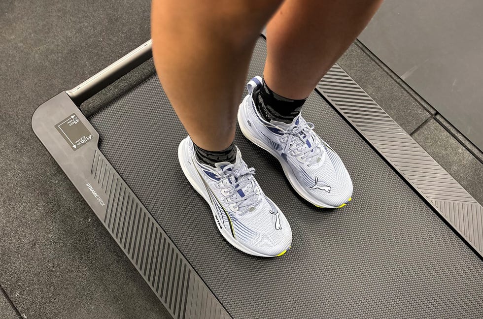 close up of someone's feet wearing purple puma running shoes on a treadmill belt