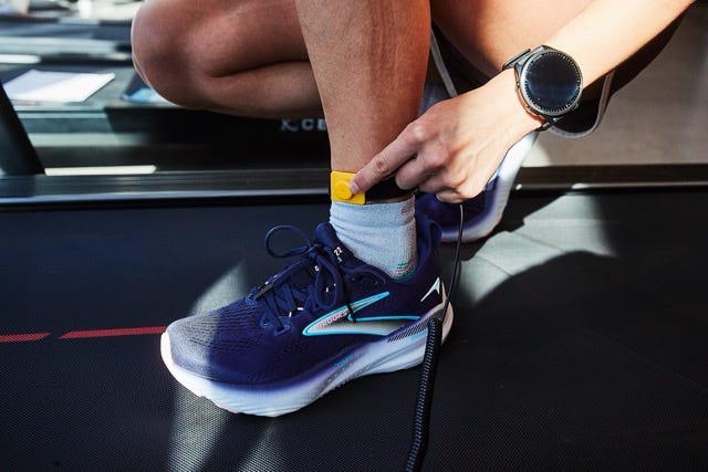 Runner adjusting a foot pod sensor on ankle during treadmill workout
