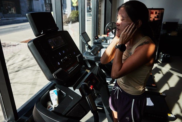 Treadmill in a gym setting with a person interacting with controls