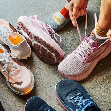 RWD A person tying shoelaces while sitting next to various running shoes