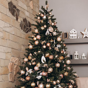 three christmas trees side by side, one decorated with sports ornaments, one with metallic ornaments, and one pink tree