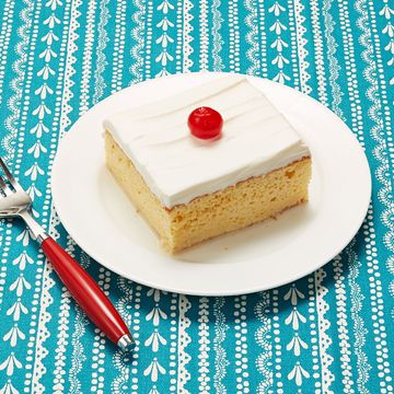 tres leches cake square slice on plate with cherry on top