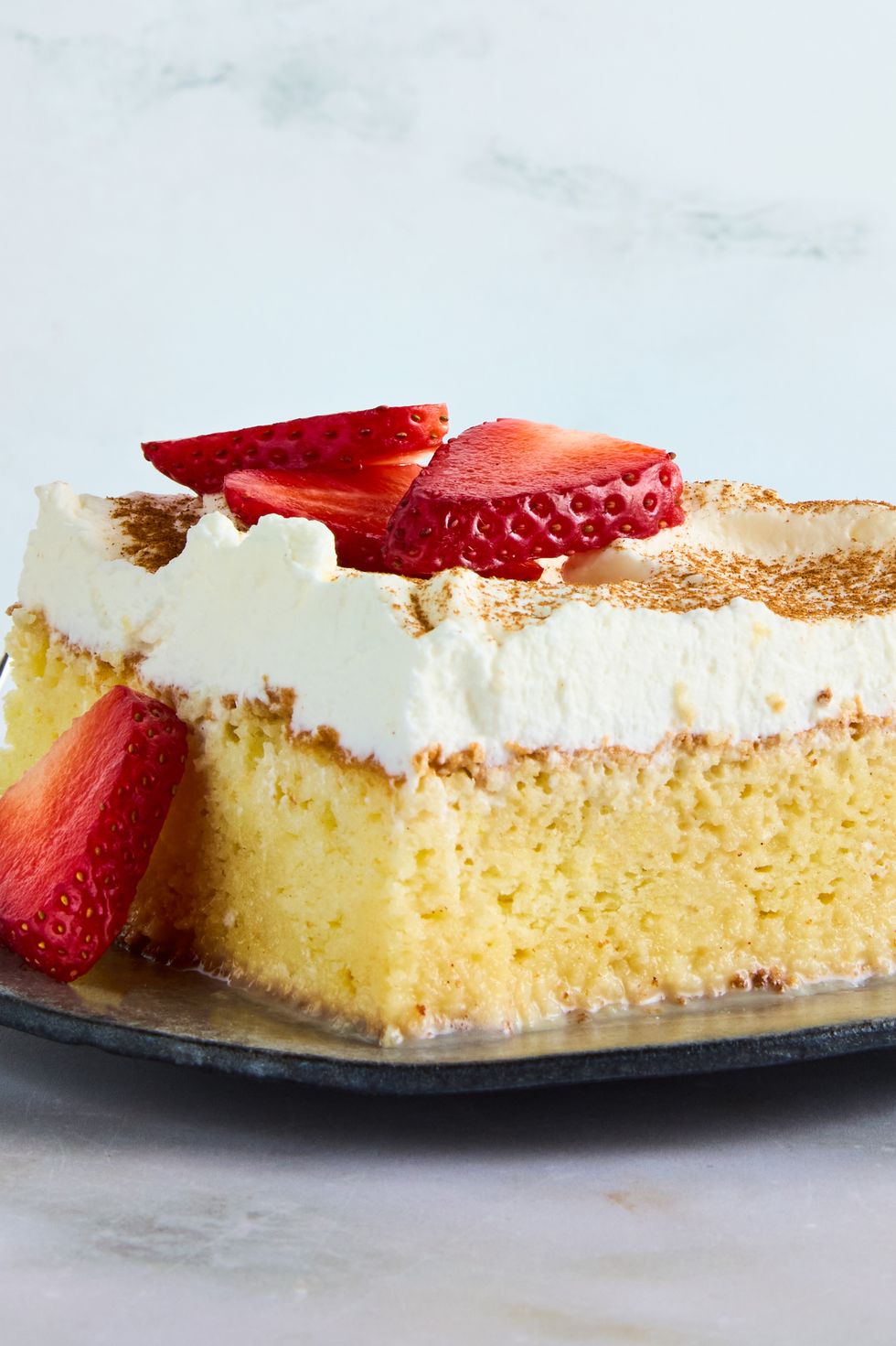 tres leches cake topped with whipped cream and cinnamon