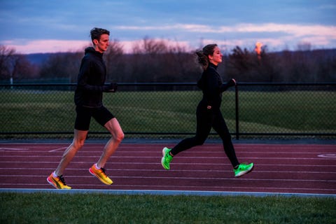 two runners on a track at sunset