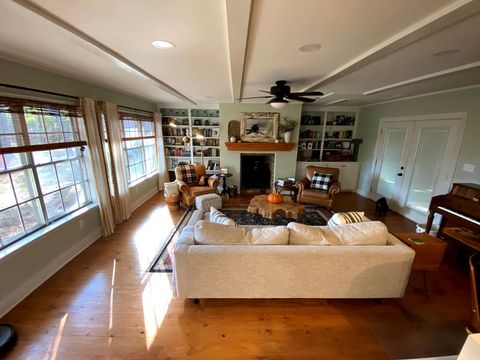 living room with fireplace, shelves, seating, and faux beams on ceiling
