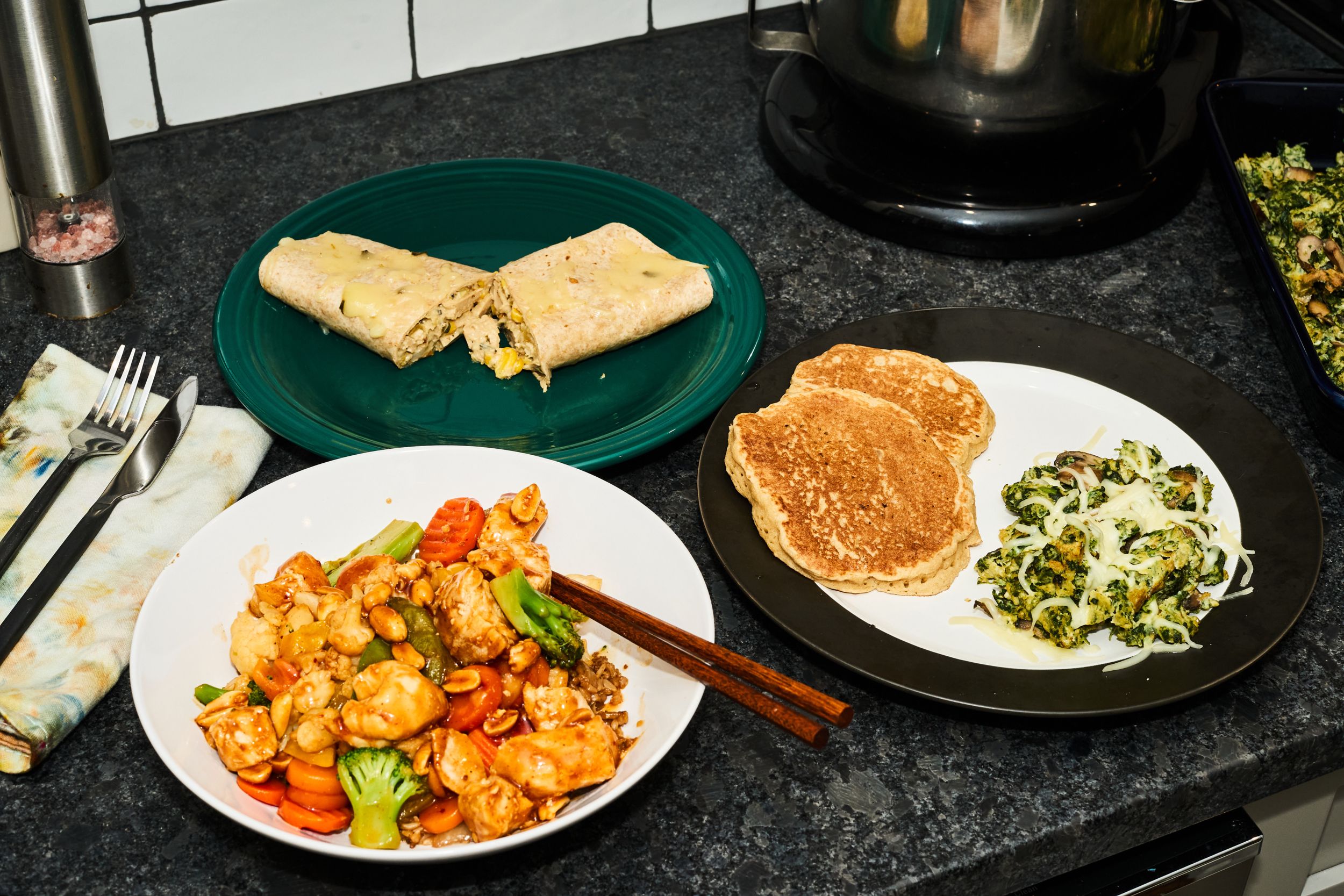 kung pao chicken, chicken enchilada, pancakes and egg, spinach and mushrooms on plates