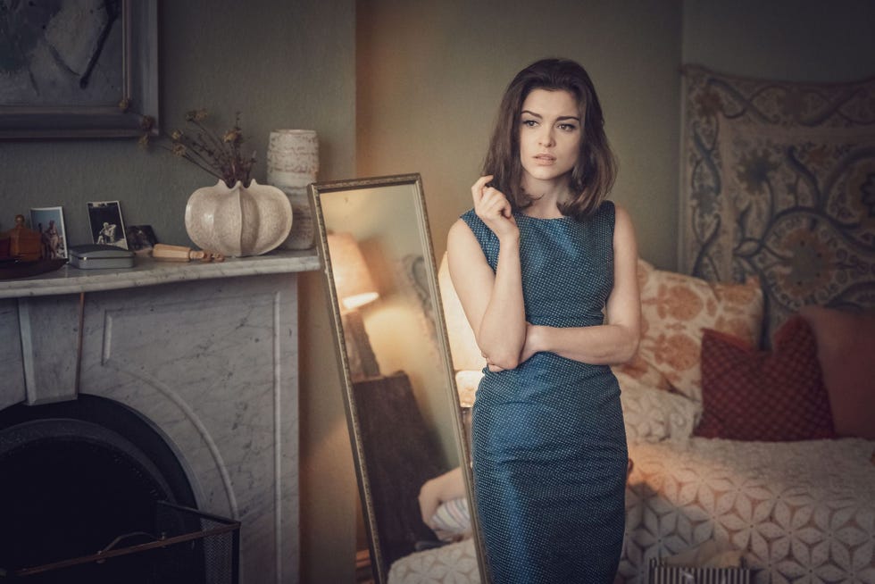 a woman stands confidently in a stylish dress in a welldecorated room
