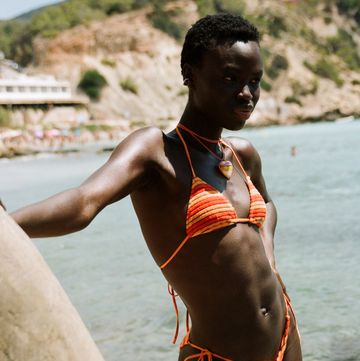 a model wears a swimsuit in front of a beach