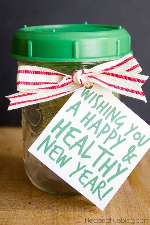mason jar with a green rubber lid, there is a card tied to a white and red striped ribbon on the jar reading "wishing you a happy and healthy new year"