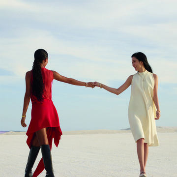 a person holding a hand of another woman on a beach