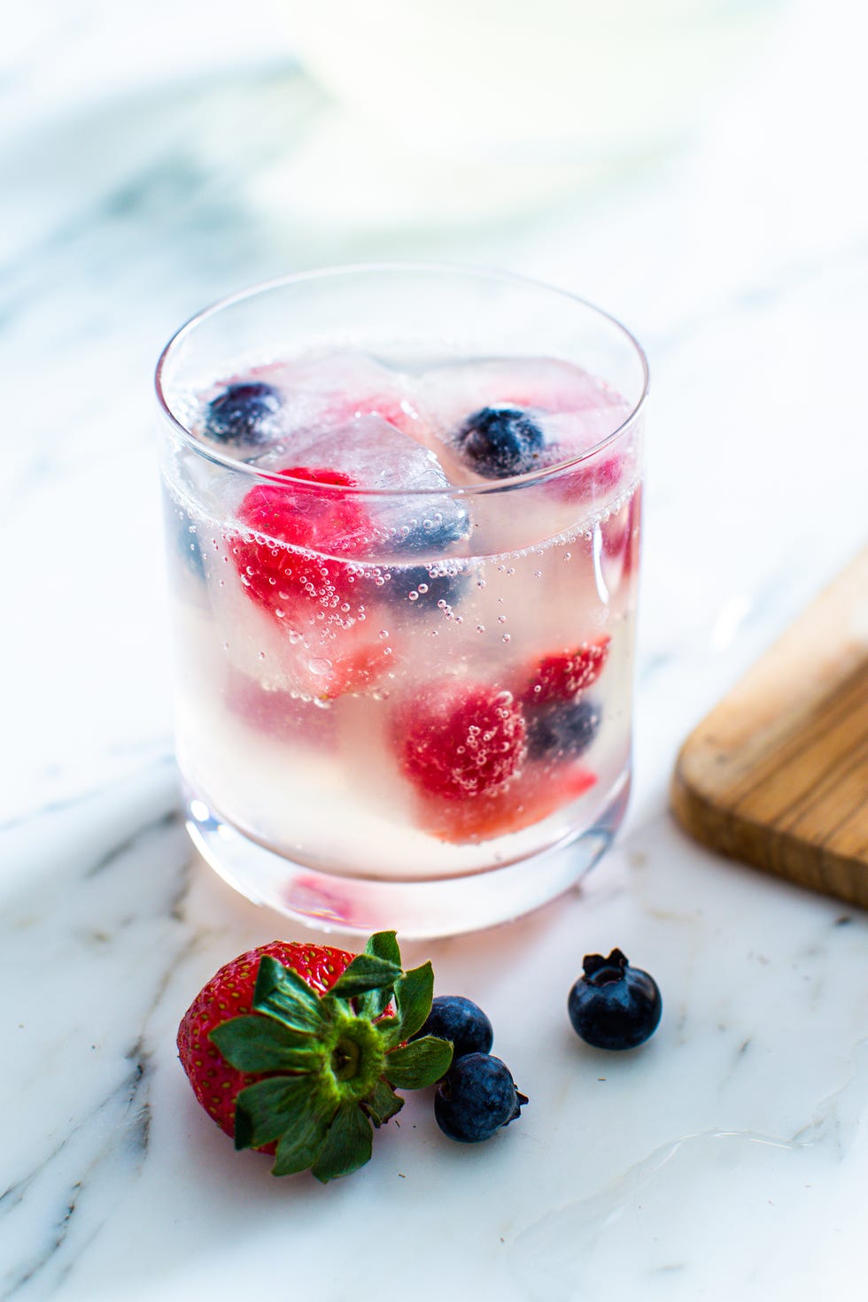triple berry sparkler mocktail with berry ice cubes in a glass
