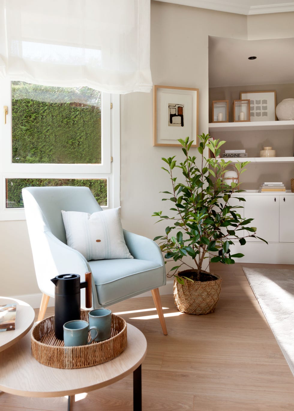 rincón de lectura con butaca azul de diseño nórdico, mesas nido de madera y acero y árbol de interior