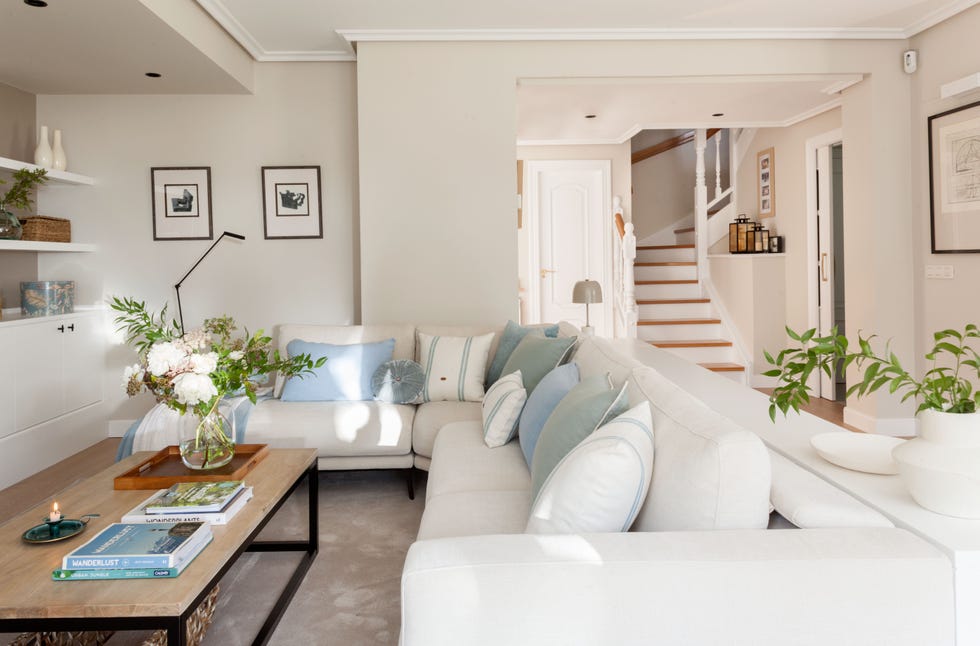 salón con sofá rinconero blanco y mesa de centro de madera y acero