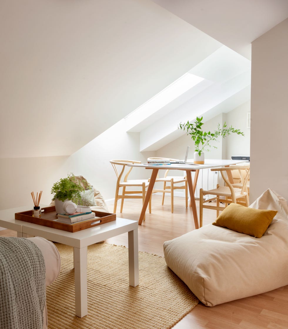 buhardilla con mesa de teletrabajo y zona relax con puf y sofá