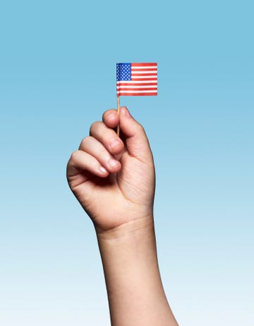 hand holding a small american flag against a blue background