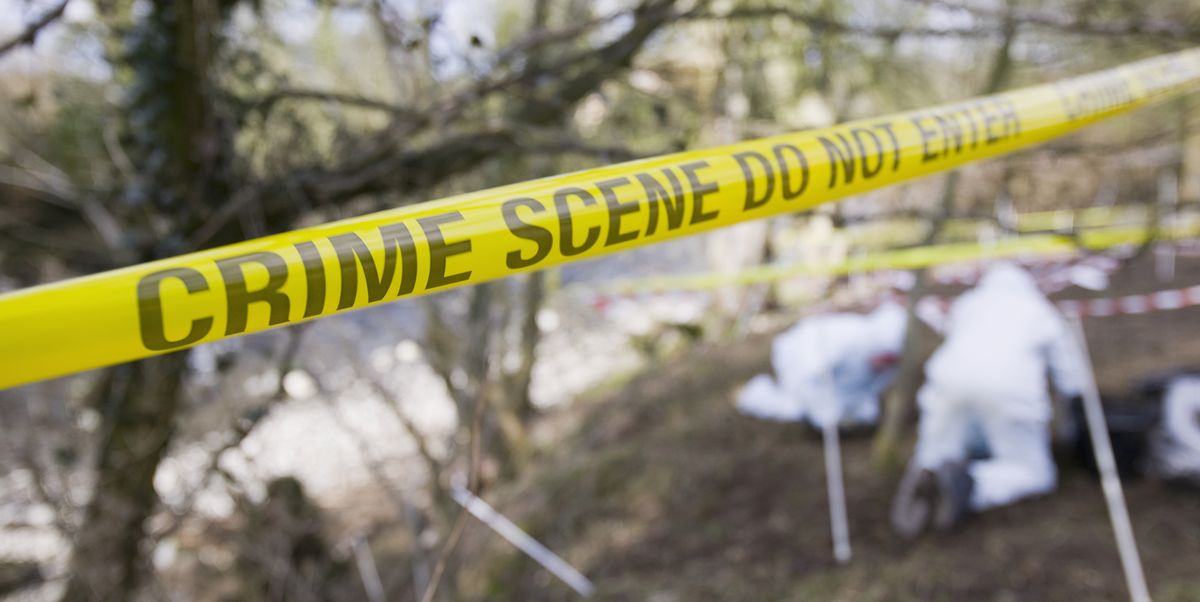 Yellow crime scene tape in front of a murder scene being investigated by police.