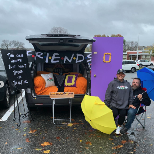 a car decked out for trunk or treat with a friends theme including colorful umbrellas and a recreation of the purple door from friends