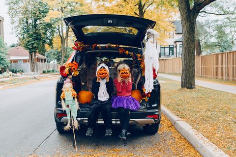 trick or trunk children celebrating halloween in trunk of car boy and girl with red pumpkins celebrating traditional october holiday outdoor social distance and safe alternative celebration