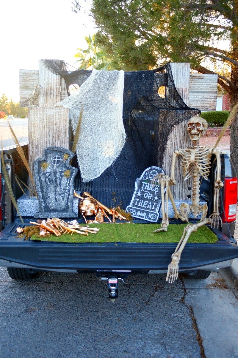 truck bed decorated with cloth and fake tombstones and golden skeletons to look like a cemetery