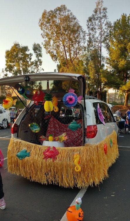 mini van trunk decked out in plastic ocean decorations and a long grass skirt