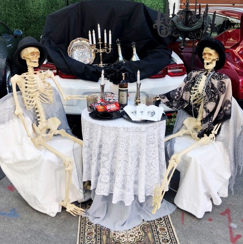 two skeletons set up for a romantic dinner for two with candles and a table cloth