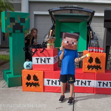 a minecraft themed trunk or treat setup features a big cardboard creeper, tnt and a kid dressed as steve