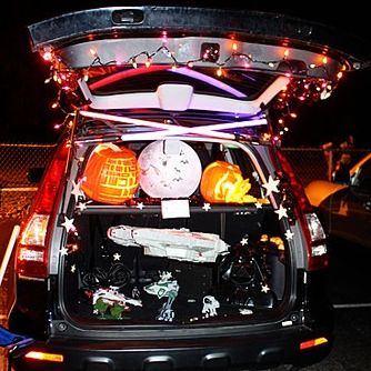 carved pumpkin death star and star wars toys make up a star wars themed trunk or treat setup