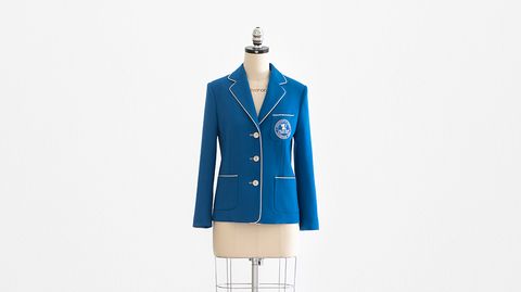a blue jacket from tory burch x billie jean king for tennis champions on a bust in front of a plain backdrop