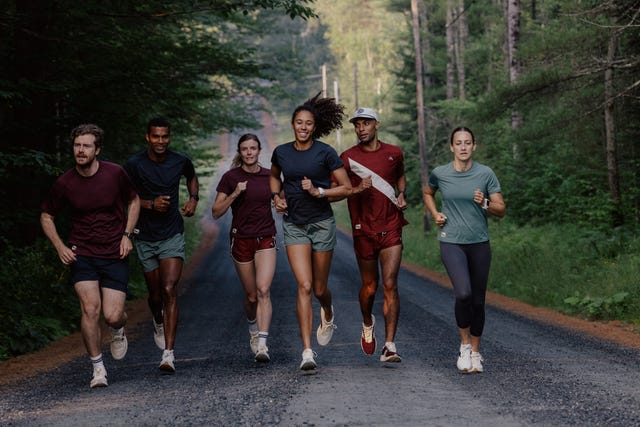 group of runners jogging on a forested road