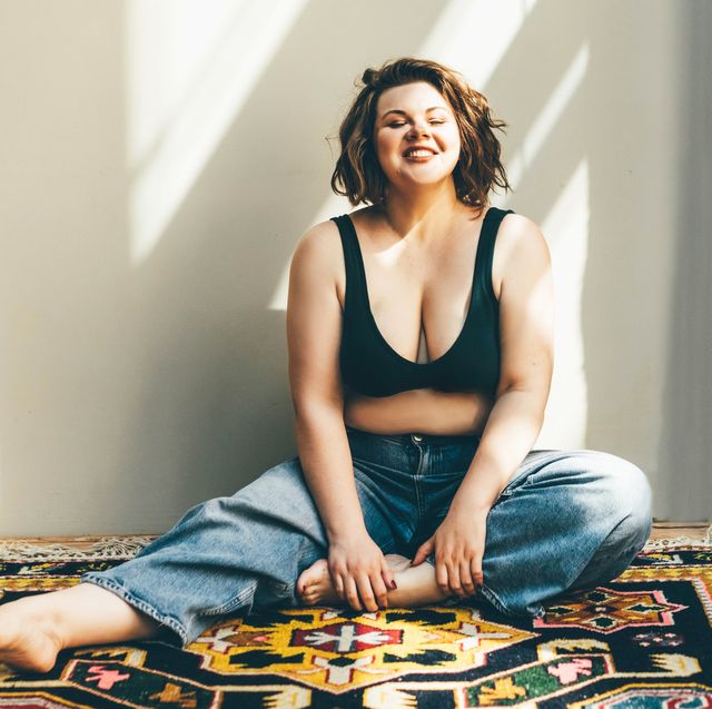 happy smiling woman sitting on the floor in bra and jeans
