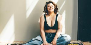 happy smiling woman sitting on the floor in bra and jeans