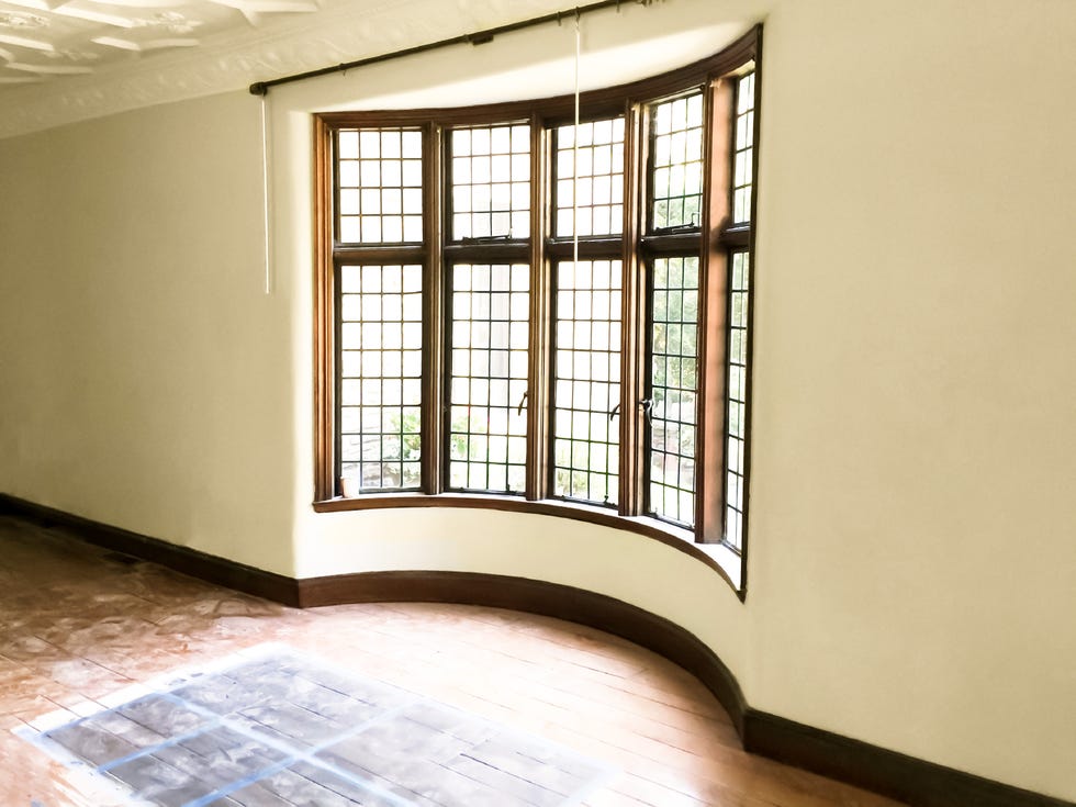 tudor home renovation selecting color of new floor stain in front of leaded glass bay window