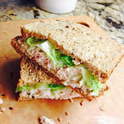 tuna fish and celery sandwich on organic whole wheat bread with gem lettuce cut in half and stacked on a cutting board