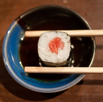 Tuna maki sushi with chopsticks in soy sauce