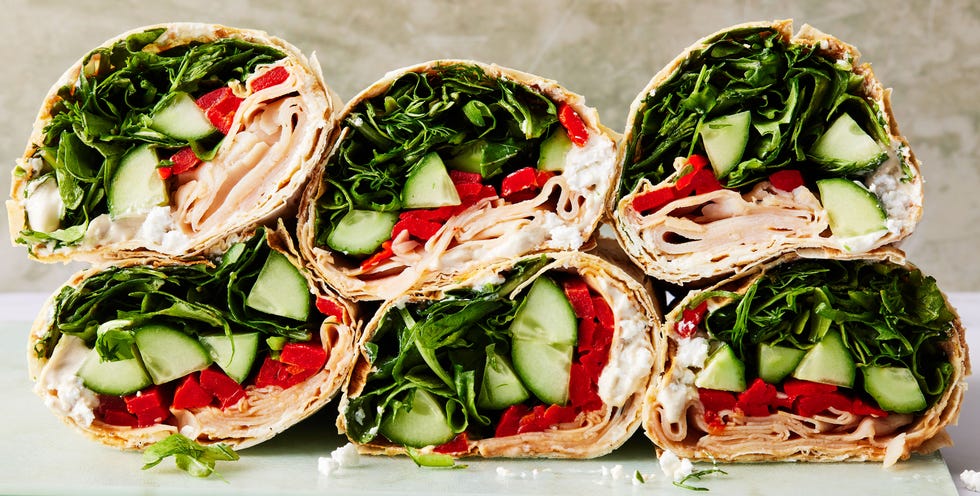 wrap filled with turkey, spinach, avocado, red peppers, and a goat cheese spread