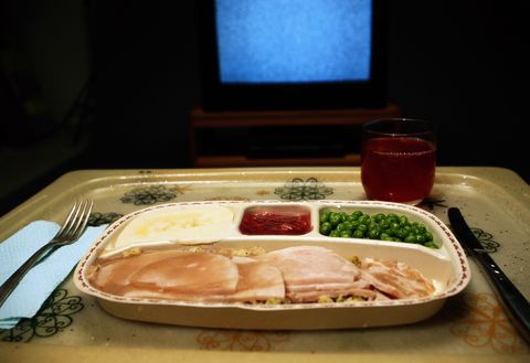 Turkey, mashed potatoes and peas dinner on tray in front of TV